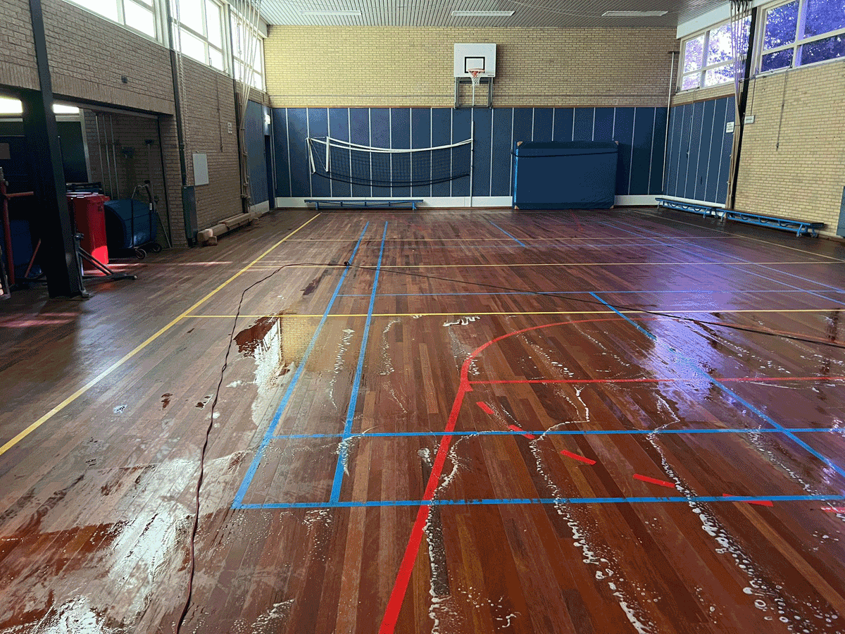 Houten sportvloer reinigen met water en machine